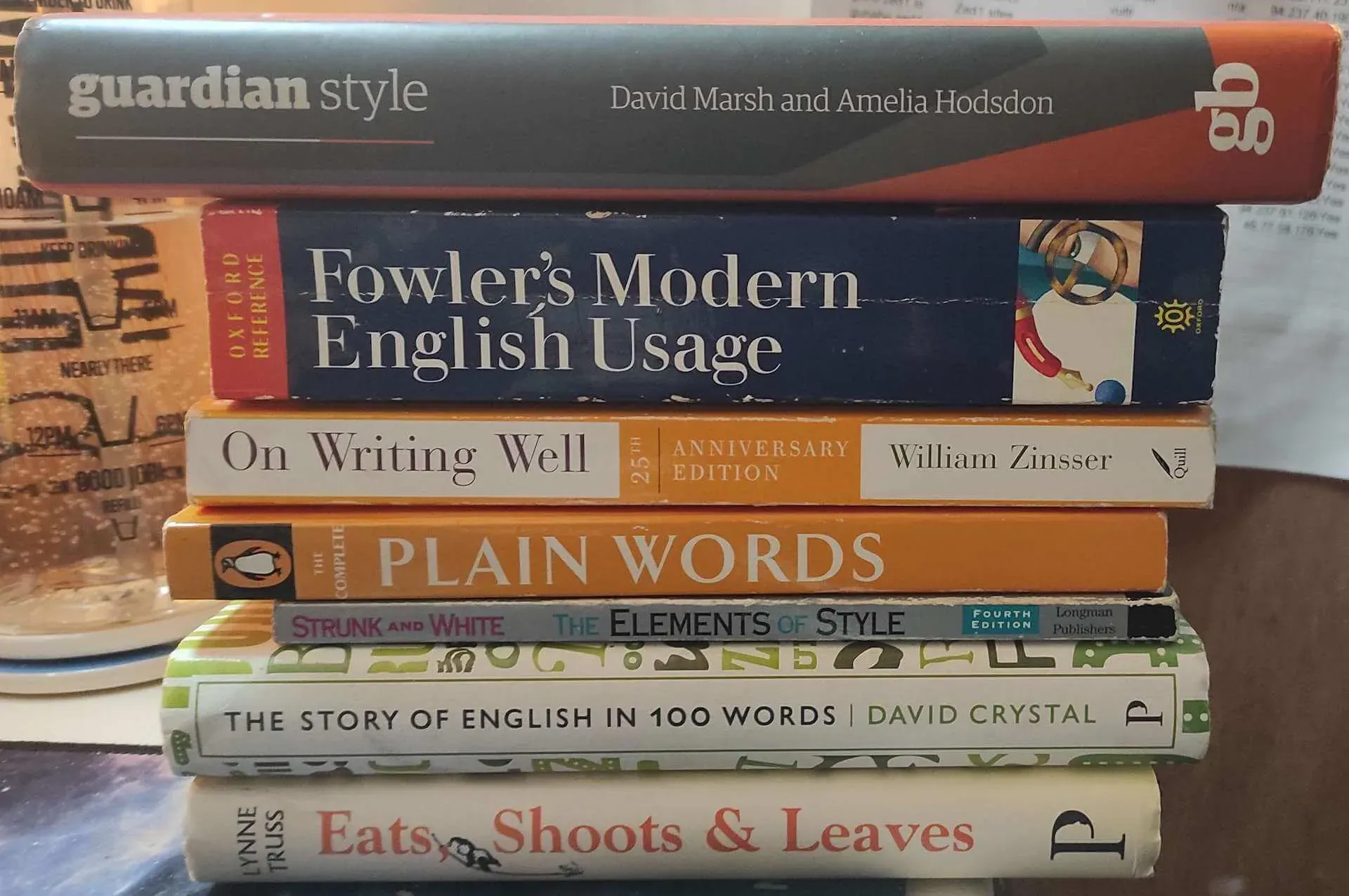 Stack of books including Guardian Style by David Marsh and Amelia Hodson, Fowler's Modern English Usage,  On Writing Well by William Zinsser, Penguin's The Complete Plain Words, The Elements of Style by Strunk and White, and The Story of English in 100 Words by David Crystal.